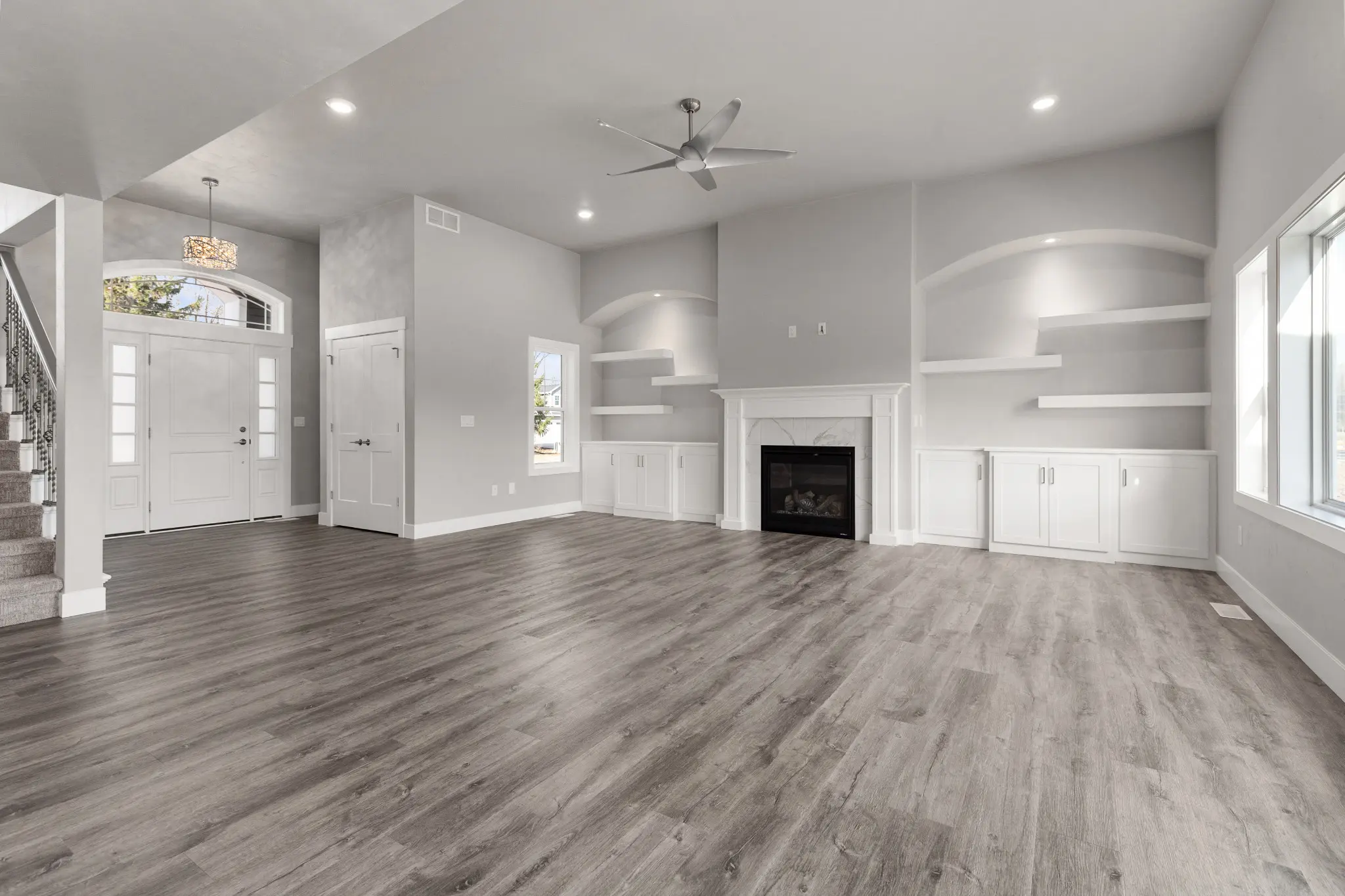 Riverwood great room with a white fireplace, built-in cabinets, and arched details