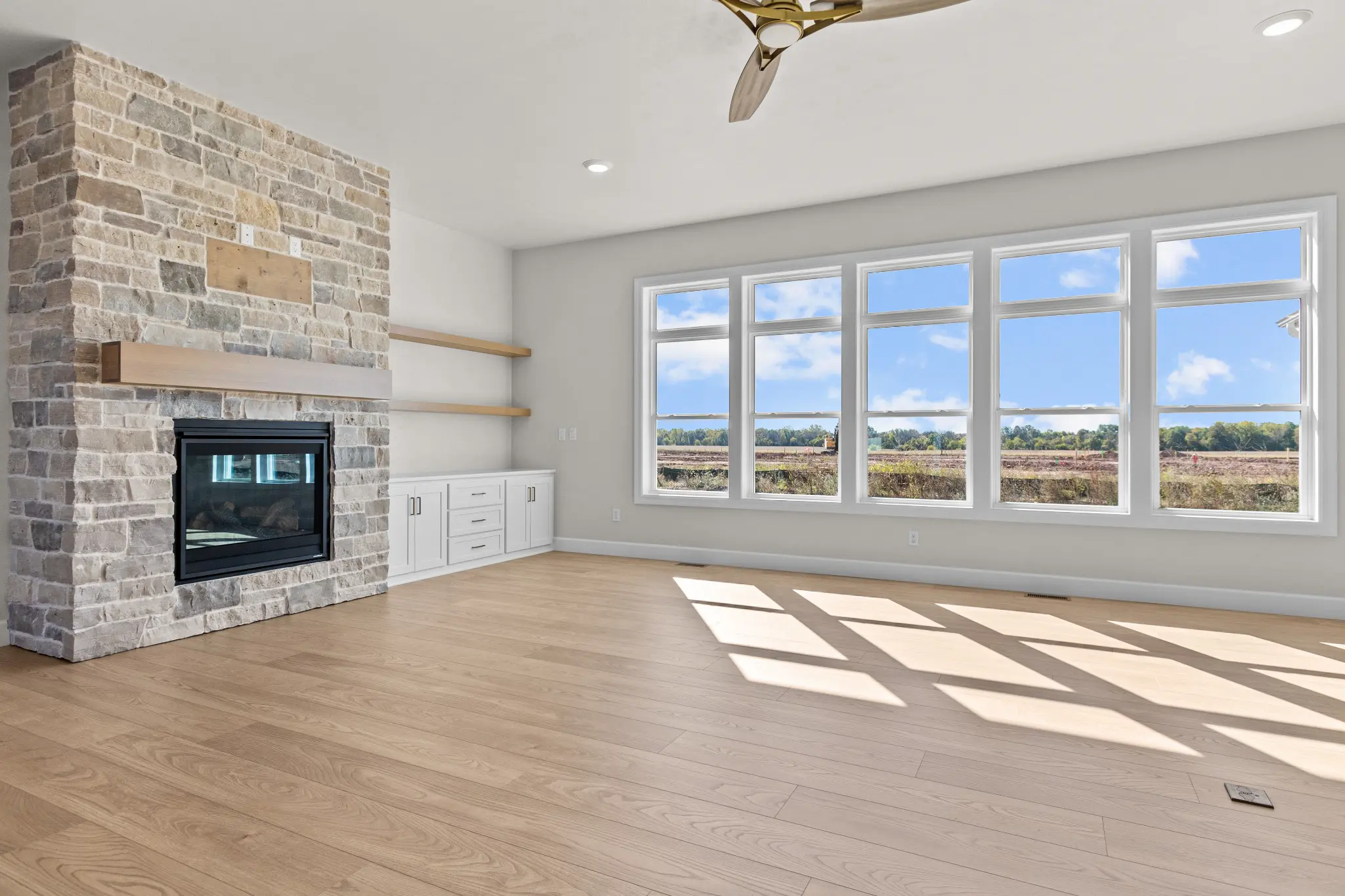 Riverwood great room with a stone fireplace and a wall of windows
