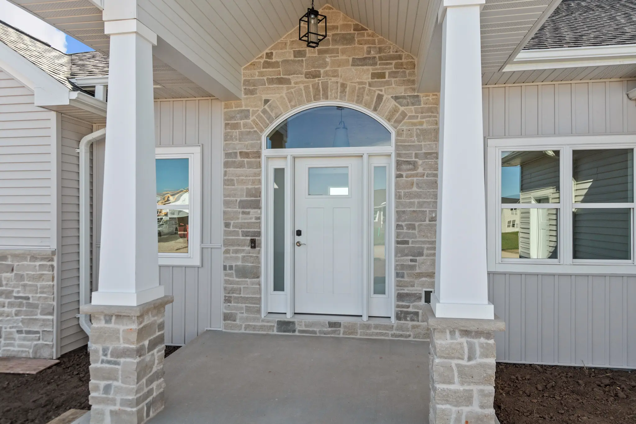 Riverwood ranch with a covered front porch, gray siding, and white garage doors